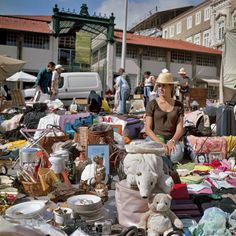 a woman sitting on top of a pile of items in front of a building with people standing around it