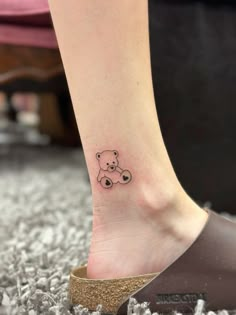 a small tattoo on the ankle of a woman's foot with a teddy bear