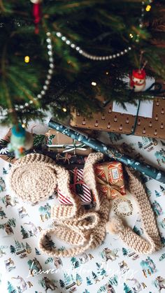 a christmas tree with presents under it on the floor next to wrapping paper and other holiday decorations