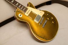 a gold electric guitar sitting on top of a white surface