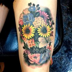 a woman's leg with flowers on it and a skull in the middle,