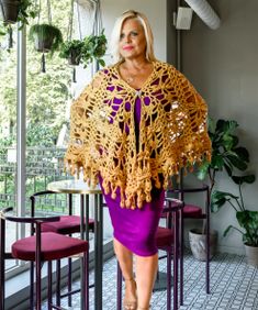 a woman wearing a crocheted shawl and purple skirt