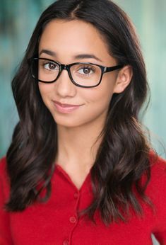 a woman wearing glasses is smiling for the camera with long hair and dark brown eyes