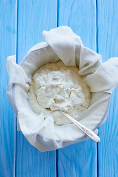 a bowl filled with mashed potatoes sitting on top of a blue wooden table next to a spoon