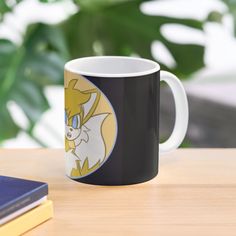 a black and white coffee mug sitting on top of a table next to a book