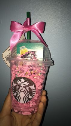 a hand holding a starbucks cup with pink sprinkles and a pink bow