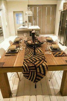 a wooden table with place settings on it in the middle of a white kitchen area