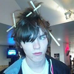 a young man with sticks on his head in a room filled with people and lights