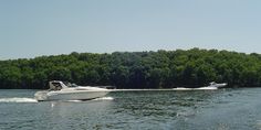 two boats are traveling on the water near trees