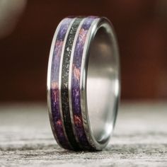 a wedding band with purple and black marble inlayed to it's sides