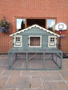 a chicken coop with a basketball hoop in front of a brick building that has a sign on it