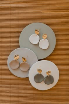 three pairs of earrings sitting on top of plates