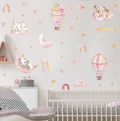 a baby's room with pink and yellow wallpaper, white crib bedding, and an air balloon mural