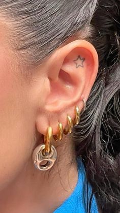 a close up of a person wearing some kind of gold earring on their left ear