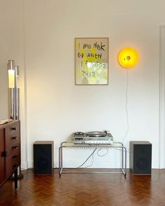 a record player sitting on top of a wooden floor next to a table with speakers