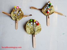 three wooden spoons decorated to look like animals with eyes and noses on them, sitting on top of a white surface