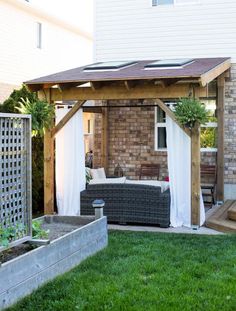 an outdoor living area with a couch and table in the grass next to a brick building