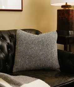 a black leather couch with a striped pillow on it and a lamp next to it