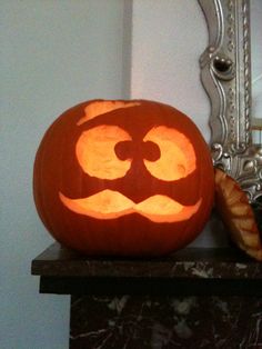 a carved pumpkin sitting on top of a table next to a mirror and a pastry