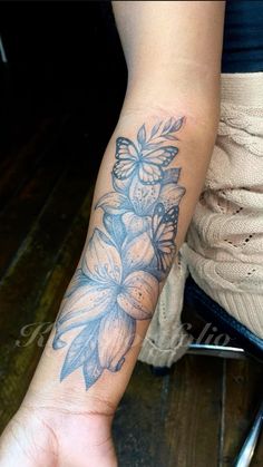 a woman's arm with a flower tattoo on the left side of her hand