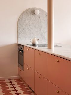 a kitchen with pink cabinets and a white tea pot sitting on the counter next to an oven