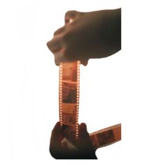 a hand holding a film strip in front of a white background with the image of someone's hand