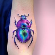 a colorful beetle tattoo on the left arm