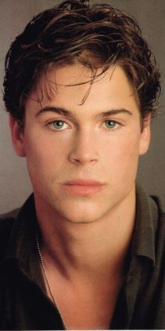 a young man with blue eyes is posing for a photo in front of a gray background