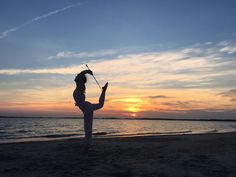 a woman doing yoga on the beach at sunset