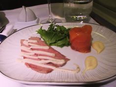 a white plate topped with meat and veggies next to a glass of water