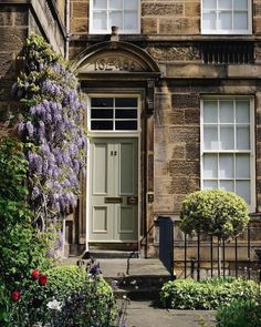 an old building with purple flowers growing on the front door and steps leading up to it