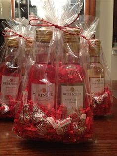 several bottles of wine wrapped in plastic and sitting on top of a wooden table with red bows