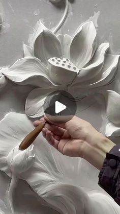 a person is painting a flower on the wall with white paint and a wooden stick