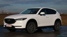 a white mazda cx - 5 parked in a parking lot next to an empty field