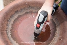 a person is using a drill to fix a hole in a planter with water