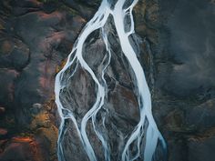 an aerial view of a waterfall with water flowing down it's sides and rocks in the background