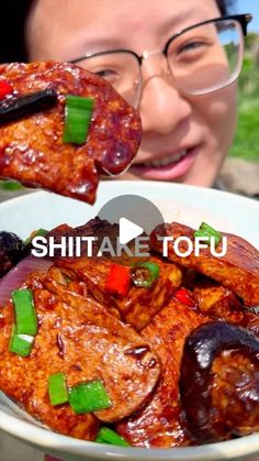 a woman is holding up some food in her hands with the caption shiitake tofu