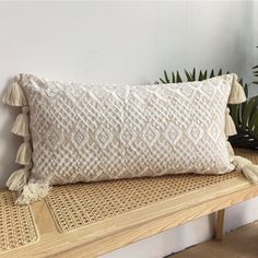 a white pillow sitting on top of a wooden bench next to a potted plant