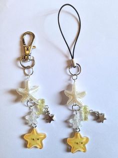 two star shaped charms hanging from hooks on a white surface with a black lanyard