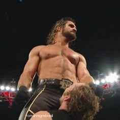 a man standing next to another man on top of a wrestling ring