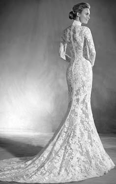 a black and white photo of a woman in a long sleeved wedding dress with an open back