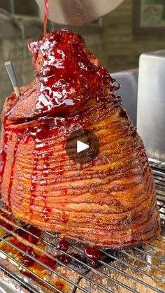 a large piece of meat sitting on top of a grill next to a cup and sauce