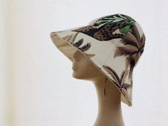 a woman's head wearing a white hat with green and brown leaves on it