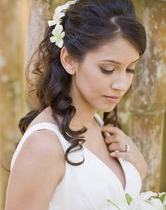 a woman in a white dress holding a bouquet and wearing a flower in her hair