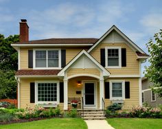 a yellow house with black shutters on the front and side windows is shown in this image