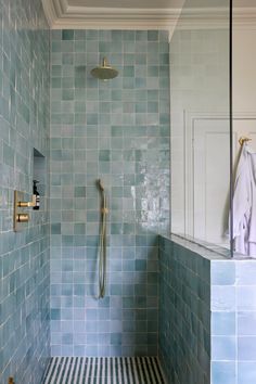 a blue tiled bathroom with a shower head