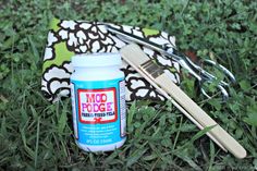 a pair of scissors sitting on top of a green field next to a jar of glue