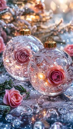 three glass ornaments with pink roses on them sitting next to christmas tree branches and lights