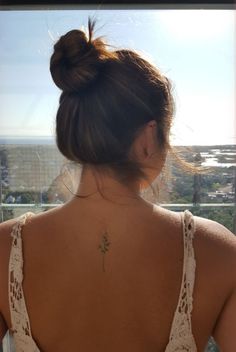 a woman with a flower tattoo on her back is looking out at the ocean and buildings