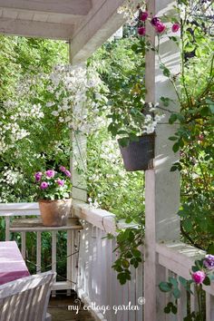 the porch is covered with pink flowers and potted greenery on it's side